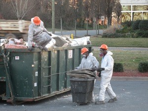 Water Damage Restoration Technicians Removing Debris To Street Dumpster