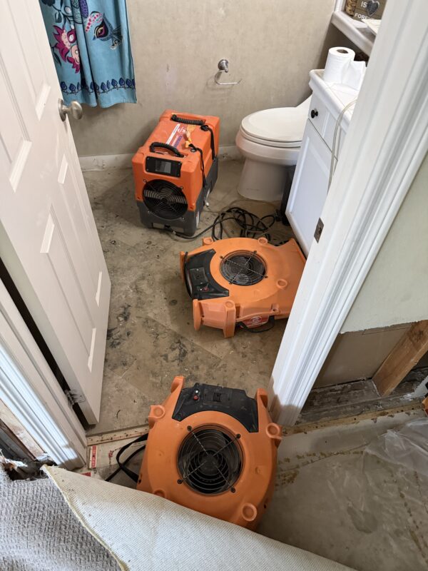 Air movers drying water-damaged flooring in a Corona California home